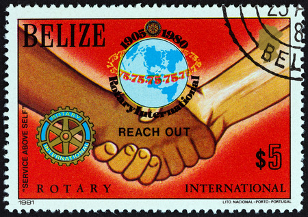 BELIZE - CIRCA 1981: A stamp printed in Belize from the "75th anniversary of Rotary International" issue shows emblems and handshake, circa 1981.のeditorial素材