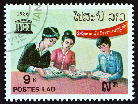 LAOS - CIRCA 1986: A stamp printed in Laos from the 40th Anniversary of UNESCO issue shows people reading books, circa 1986.のeditorial素材
