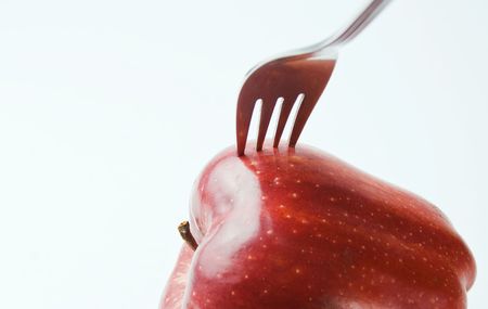 Red apple with a fork over white backgroundの写真素材
