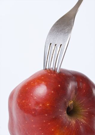 Red apple with a fork stuck in studio lighting conditionsの写真素材