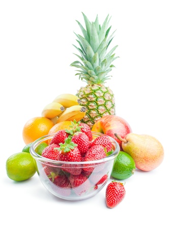 	Fruits. Arrangement of various fresh ripe fruits: pineapple, bananas, oranges, pear, apple, limes and strawberries in a glass bowl isolated on white backgroundの写真素材