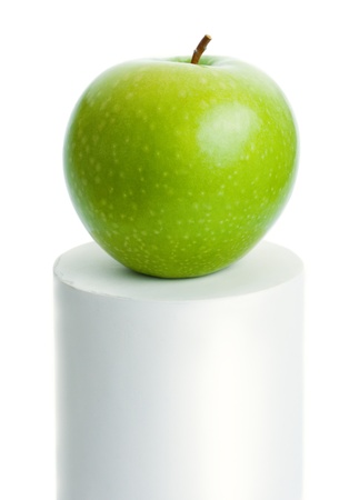 Green apple. Fresh ripe green apple placed on top of a white cylinder isolated on white background.の写真素材