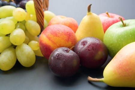 Fruits. Mix of fresh ripe fruits close-up: plums, peaches, pears, apples and grapes on neutral background.の写真素材