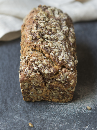 A loaf of whole-grain bread on a dark stone plate