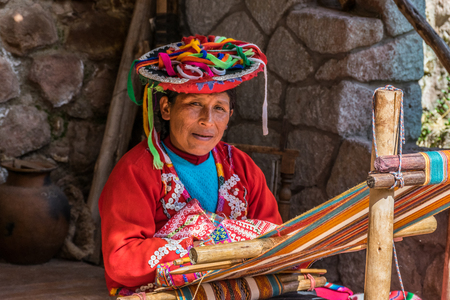 Local village woman making colorful handmade textiles at the Awanacancha Textile site in Peru outside of Cusco.のeditorial素材