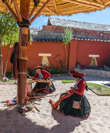 Local village women making colorful handmade textiles at textile site in Chinchero, Peru.のeditorial素材