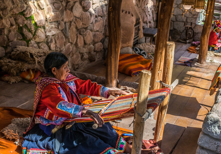 Local village woman making colorful handmade textiles at the Awanacancha Textile site in Peru outside of Cusco.のeditorial素材