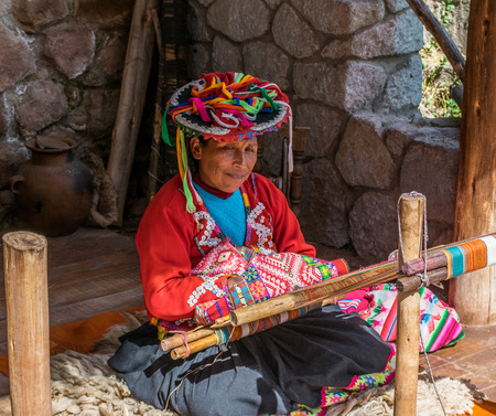 Local village woman making colorful handmade textiles at the Awanacancha Textile site in Peru outside of Cusco.のeditorial素材