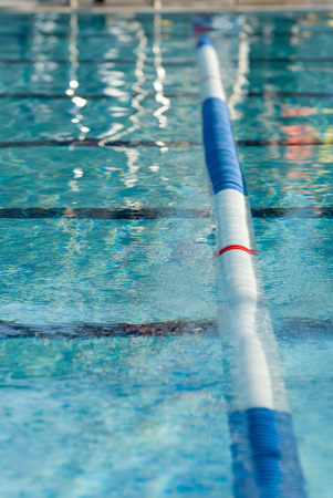 Picture of a lane line in a outdoor swimming pool. Focus centered on the red stripe on the lane lineの写真素材