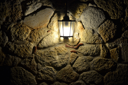 Street lamp illuminates the stone wall at nightの写真素材