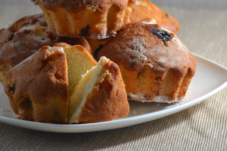 Fresh buns with raisins on a white plate close-up.の写真素材