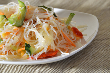 Salad funchoza with vegetables on a white plateの写真素材