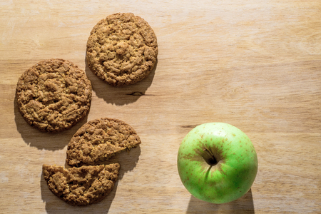 Oatmeal cookies on a wooden board with green appleの写真素材