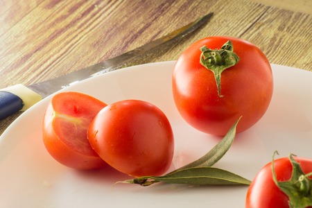 Group of tomatoes on a plate with a knife on the tableの写真素材