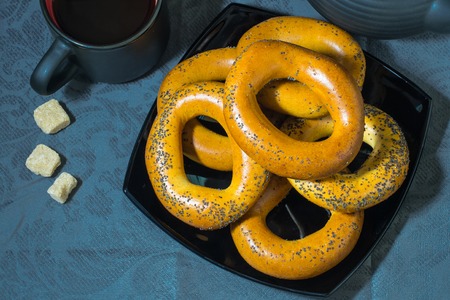 Many large bagels on a black plate and sugar on a blue tableclothの写真素材
