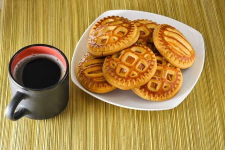 Cookies on a plate and a cup of black coffee.