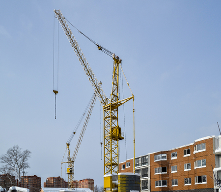 Abandoned construction of a multi-storey building. Tower crane, and a house with broken glass. Winter. Russiaの写真素材