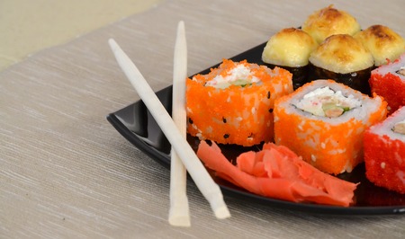 Sushi and rolls on a black plate with chopsticks.の写真素材