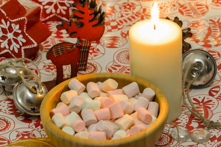 Marshmallow in a wooden plate. Lighted candle on the table. New Year's compositionの写真素材