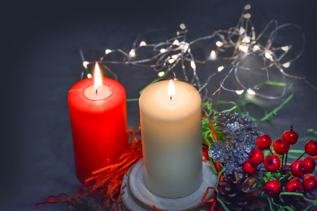 Christmas composition: red and white burning candles on a festive table on a dark background. Gingerbread, tinsel, festoon. Christmas, New Year, holidayの写真素材