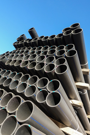 Plastic pipes in the assortment of finished products packed in packages against a blue skyの写真素材