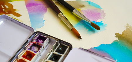 Set of watercolor paints and paintbrushes for painting closeup. Selective focus.