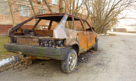Abandoned burned passenger car near the apartment building. Russia.の写真素材