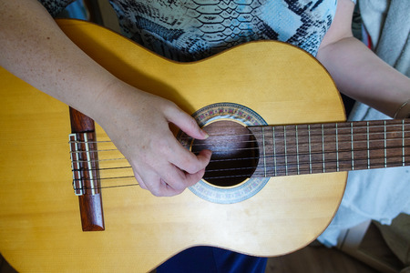 Female hand playing on acoustic guitar. Close-up.