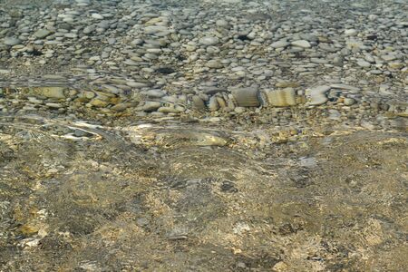 Sea stones in the sea water. Pebbles under water. The view from the top. Nautical background. Clean...