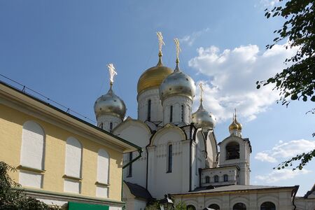 Golden domes with crosses of an orthodox temple on the background of bright blue sky. Snow-white...
