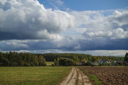 Green field with a country road and sky with clouds. Russiaの写真素材