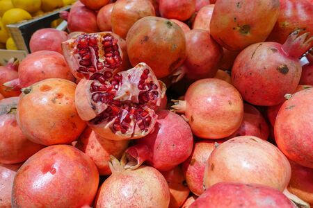 Broken pomegranate on a pile of red pomegranates in the marketの写真素材
