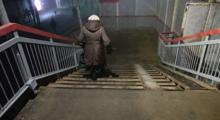 An elderly woman walks down the crossing bridge. Night Russia.の写真素材