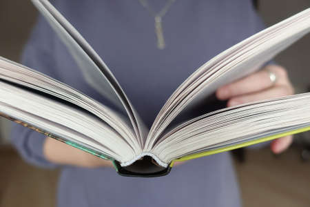 Girl holding an open book in front of herの写真素材