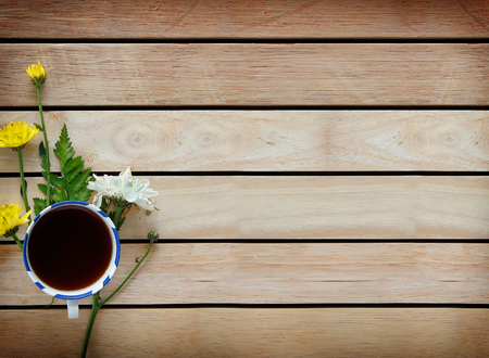 A cup of tea with flowers and tea around it are on wooden background.の写真素材