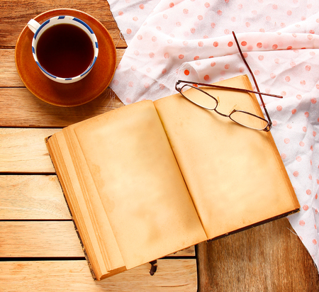 A cup of black tea with vintage book are on wooden background.の写真素材