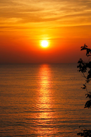 Big orange sunset over the sea in the evening with horizontal streaks waves in the middle of the evening sea. Natural background concept.の写真素材
