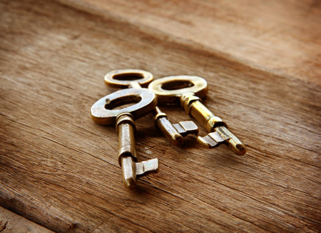 Vintage golden keys are on a wooden background for the mysterious, elegant vintage bannerの写真素材