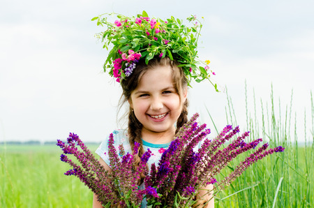 Happy cheerful girl with floral headband on head. Summertime multicolor outdoors horizontal image.の写真素材