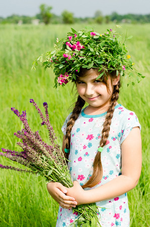 A little pretty girl in picking flowers in the field of flowering on a sunny summer day. Kids and nature. Children in country. Beautiful floraの写真素材