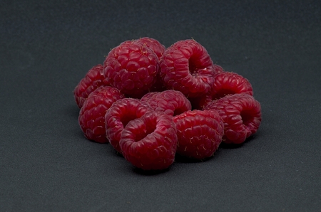 Raspberries over black background