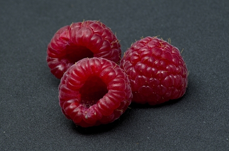 Raspberries over black background