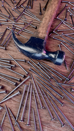 Old stained iron hammer on wooden table surrounded with nails. 3D illustrationの写真素材