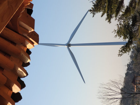 Wind turbine on the roof of a wooden house against the blue skyの写真素材