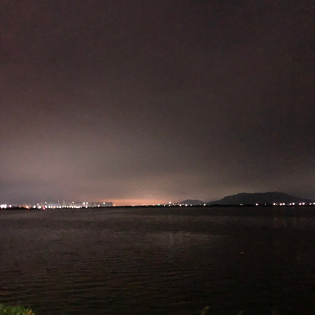 Night view of the city from the shore of the lake. The sky is dark.の写真素材