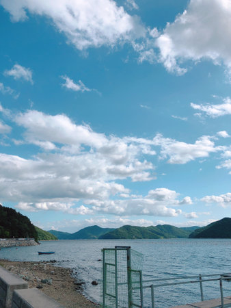 Landscape view of lake and mountains under cloudy blue sky in summerの写真素材