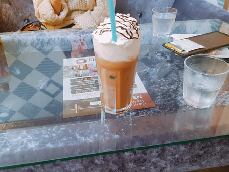 Iced coffee with whipped cream on the table in coffee shop.の写真素材