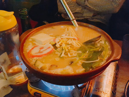 Japanese noodle soup with tofu in a pot on a wooden tableの写真素材