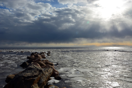 Sun through the stormy clouds at the frozen sea with broken ice