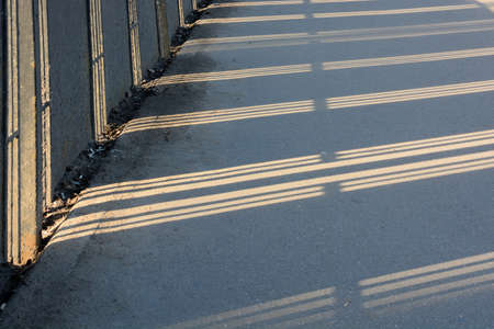 Shadow from the fence on the road on a sunny winter day. Fancy pattern, reflectionの写真素材